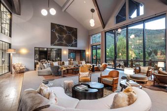 A spacious and elegantly furnished living room at Riverbend House with large windows offering mountain views, comfortable seating, and modern decor.