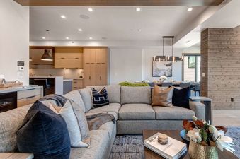 The living area at Abode at Powder King features a large sectional sofa with various pillows, a coffee table with decor, and a view into the adjacent kitchen and dining spaces.