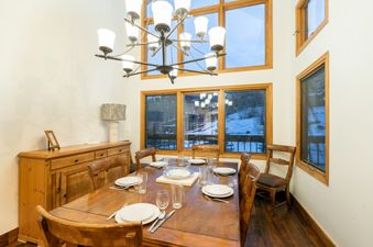 The dining area at Kayenta II 16 features a large wooden table set for dinner under an elegant chandelier.