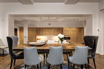 The dining area in Abode at the Parkite features a long wooden table with seating for eight.