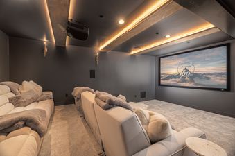A luxurious home theater with plush seating, dim lighting, and a large screen displaying the Paramount Pictures logo.