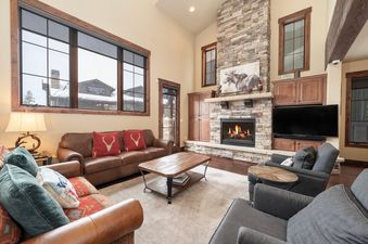 The inviting living area at 751 Mountain Terrace boasts a comfortable brown leather sofa, plush armchairs, and a warm, crackling fireplace.