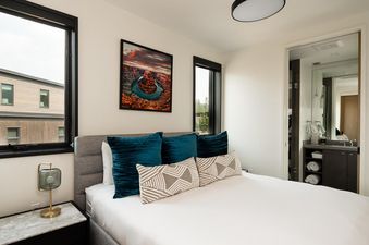 The bedroom at Moonlight Basin 12A Treeline features a comfortable king-size bed with plush bedding, a cozy sitting area with a plush armchair and ottoman, and a large window with views of the surrounding mountains.