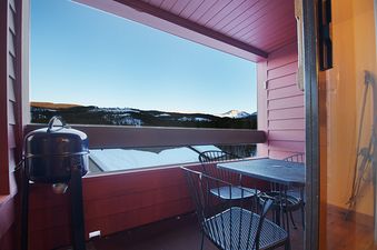 A close-up view of the outdoor patio with a grill and patio furniture, offering a stunning mountain view.