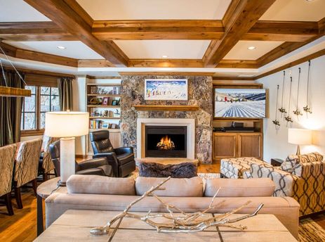 A spacious and luxurious living room with a large stone fireplace, comfortable sofas, and a dining area in the Chateau Beaver Creek Residence 1304.