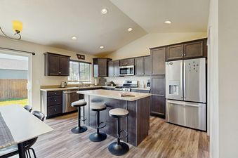 A modern kitchen with dark wood cabinets, light granite countertops, and stainless steel appliances.
