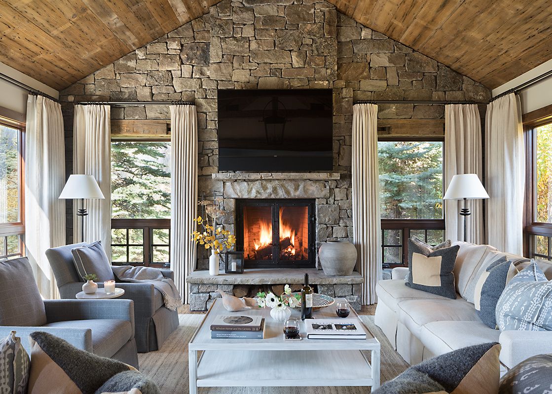 The living area of Shooting Star Cabin 11 features a stone fireplace, comfortable sofas, and large windows with scenic views.