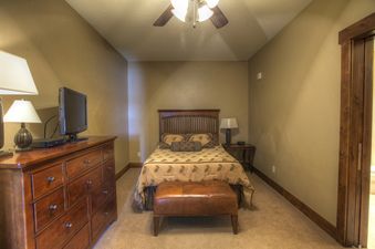 The Crystal Peak 3 Bedroom features a comfortable queen-sized bed, complete with a dark wooden headboard and a patterned comforter, complemented by matching pillows.