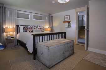 The bedroom at The Bluebird Cottage, featuring a queen-sized bed, decorative pillows, and unique wooden furniture.