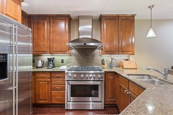 A modern kitchen with stainless steel appliances, granite countertops, and wooden cabinetry in Ascent 405.