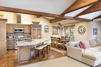 The Chateaux Four Bedroom Suite features an open concept kitchen, dining, and living area with wood beamed ceilings.