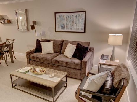 The living area of Aspens on Blackcomb Unit 304 features a comfortable brown sofa, a modern coffee table, and a stylish armchair, complemented by soft lighting and decorative accents.