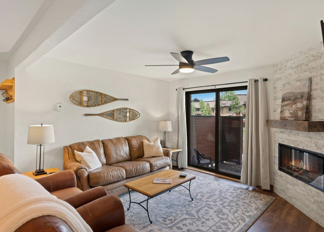 A living room with a leather couch, a coffee table, and a fireplace.