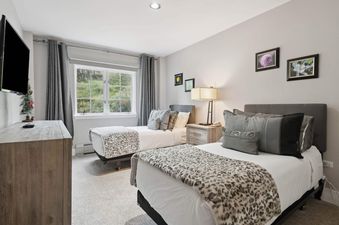 Two twin beds with patterned blankets and grey pillows are in the room.