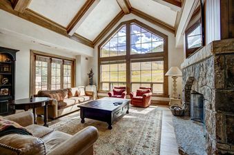 The living area of the Golden Peak 4BR Penthouse features a comfortable seating arrangement around a large wooden coffee table and a stone fireplace.