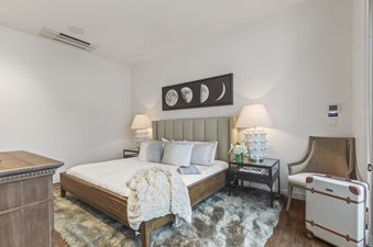 A serene bedroom at Parkite 37 with a plush bed, stylish lamps, and moon phase artwork above the headboard, creating a tranquil and inviting atmosphere.