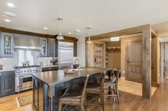 A modern kitchen with stainless steel appliances, dark wood cabinets, and a large island with seating for three.
