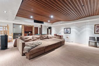 A spacious lounge at Silverado featuring a large modular brown sofa, unique wooden ceiling, and entertainment amenities in the background.