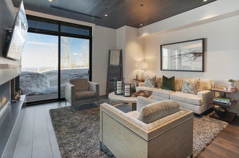 Living room with a large window overlooking a snow covered landscape.