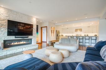 A modern and cozy living room and kitchen area with a fireplace and stylish furniture in Snow Cloud Lodge 509.