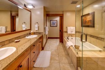 A luxury bathroom with a large walk-in shower, a bathtub, double sinks, and a marble countertop.