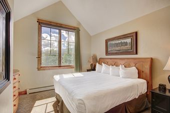 A cozy bedroom in Mountain Thunder 2 Bedroom TH with a large window and wooden furniture.