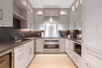 A modern galley kitchen at Solaris PHCE with light gray cabinets, dark gray countertops, and stainless steel appliances.