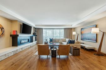 The living area of the St Regis 2 Bedroom Snow Park features a fireplace, a large sectional sofa, two accent chairs, and a large window.