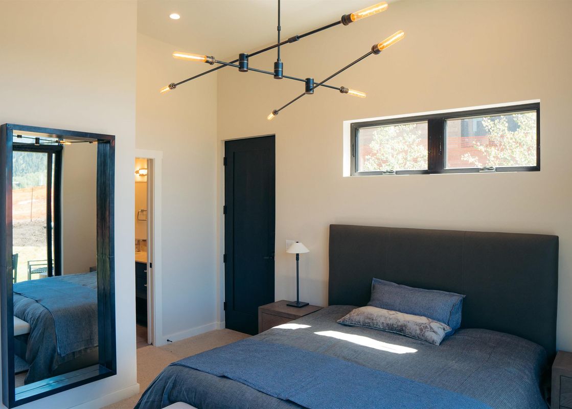 A modern bedroom with a comfortable bed, stylish lighting, and a view of the outdoors at The Lodge Cabins Four Bedroom Meadow Cabin.