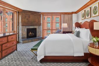 A bedroom at the St Regis Residence Club 3 Bedroom, with a king-size bed, a fireplace, and a window overlooking the city.