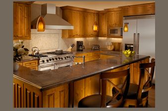 A modern and warm kitchen with wooden cabinets, granite countertops, and stainless steel appliances.