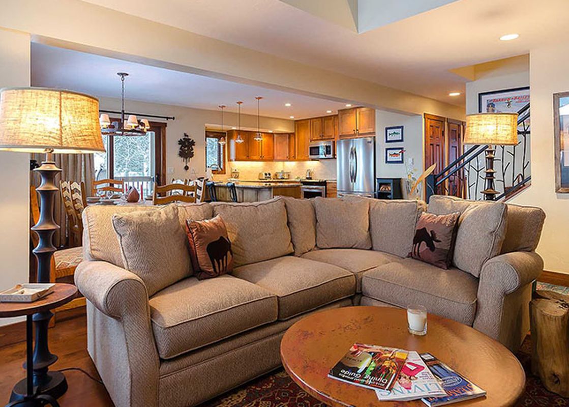 An upside-down interior view of a living room and kitchen in the Ranch at Steamboat RA520, featuring an L-shaped sofa, coffee table, and fully equipped kitchen.