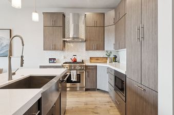 A modern and sleek kitchen at Holly Frost Chalet with wood cabinets, quartz countertops, and stainless steel appliances.