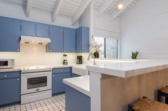 A white kitchen with blue cabinets and a white stove.