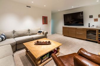 A cozy living area in Roaring Fork Chalet with a comfortable L-shaped sofa, a large flat-screen TV mounted above a stylish media console, and a wooden coffee table with decorative pinecones.