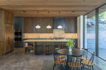 Modern kitchen with wooden cabinets, a large island, and a dining area with a round table and chairs.