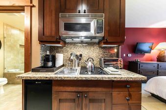 A small kitchenette with a microwave, stovetop, and sink in a vacation rental.