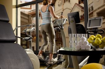 A woman working out on an elliptical trainer in the modern gym of the Arrabelle King Suite.