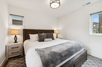 A modern and serene bedroom at Quarry A4 with a large bed, nightstands, lamps, and windows.