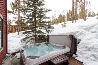 A hot tub on a wooden deck in a snowy outdoor space.