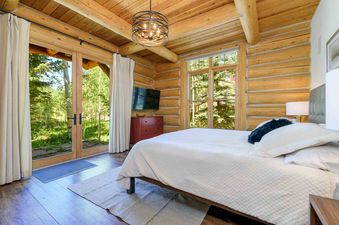 The bedroom in Wild Cat Lair features a log cabin design and a beautiful view of the surrounding forest.