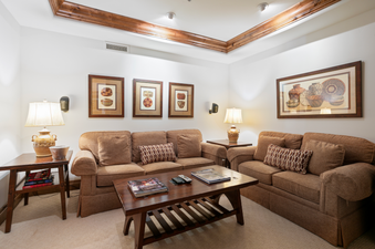 Relax on the comfortable brown couches in the living room of the Grand Lodge Three Bedroom Deluxe 404 with a book or watch TV.