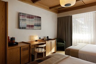Mollie Aspen Smuggler Double Queen features a stylish bedroom with two queen beds, a wooden desk, and an elegant lamp.