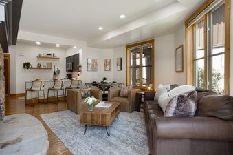 The open-concept living area in 118 Villa Montane features a cozy seating arrangement, a modern kitchen with a breakfast bar, and a dining area, all bathed in natural light.
