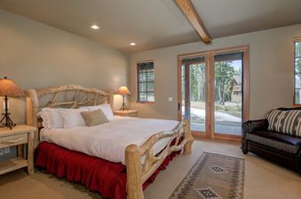 A large bedroom with a king-sized bed, a wood-burning fireplace, and a view of the mountains.