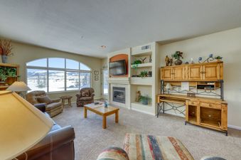Living room with a fireplace, a large window with a view of snow-capped mountains, and a wooden cabinet with doors.