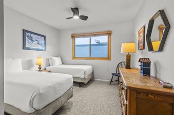 A twin bedroom at Snow Flower 41 Park City with two beds, a wooden dresser, and a window.