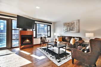 A cozy living room in Lowell 303 with a fireplace, comfortable leather seating, and hardwood floors.