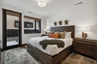 A master bedroom at Huckleberry Haven featuring a king-sized bed, wooden headboard, rustic decor, and direct outdoor access through a glass-paned door.