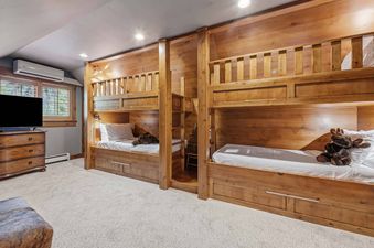 A cozy bunk room in Buckhorn Townhome 264 features two wooden bunk beds with white bedding, individual reading lamps, and recessed lighting.